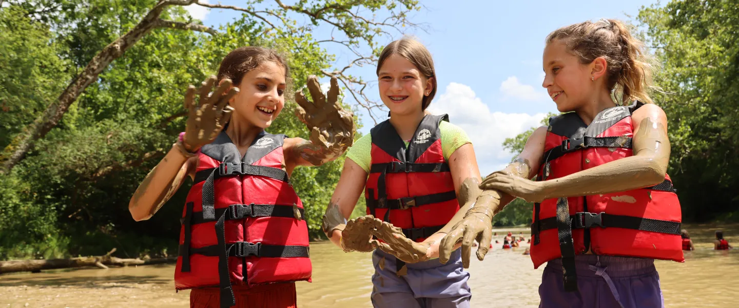 girls playing in mud at the river
