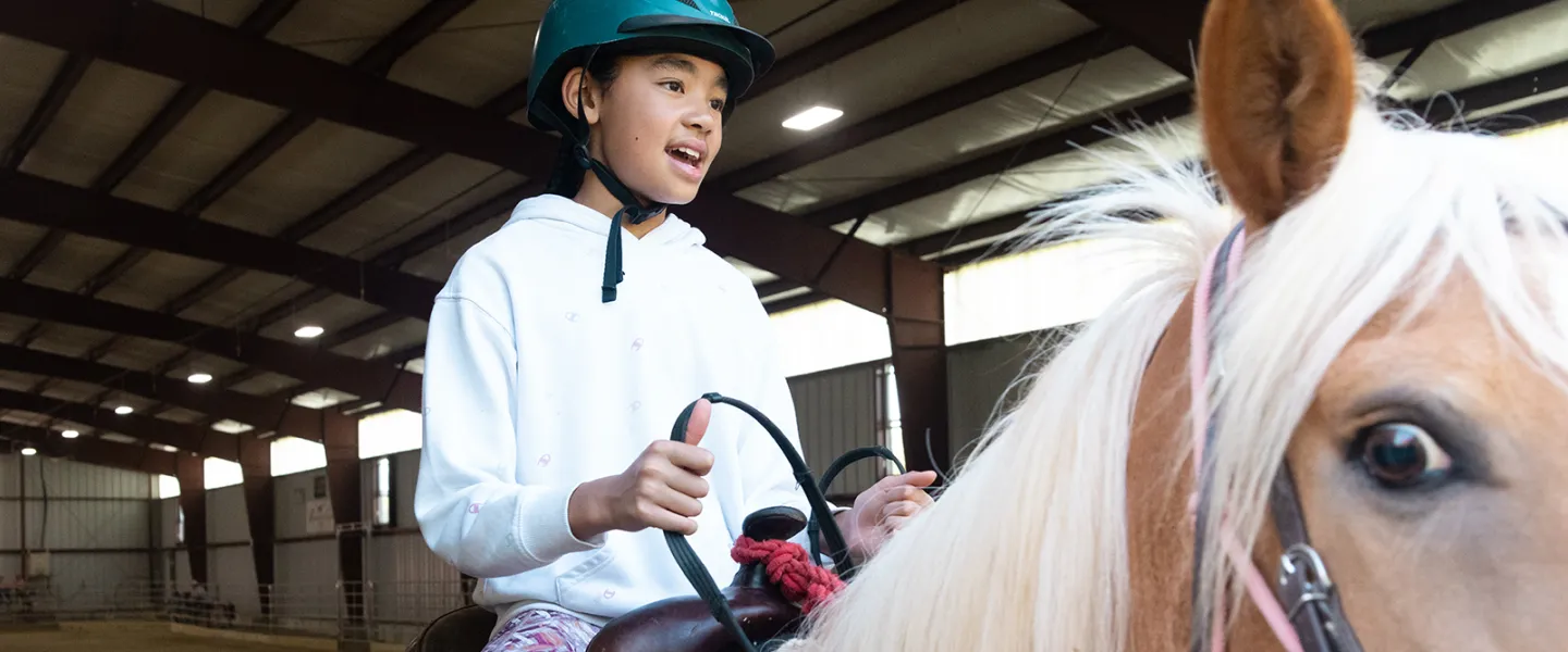 A girl riding a horse at camp
