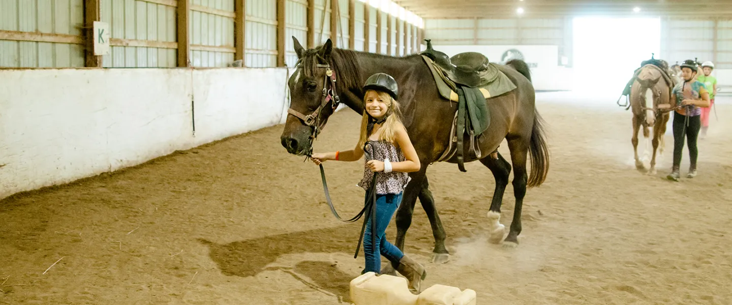 A girl walking with a horse at camp