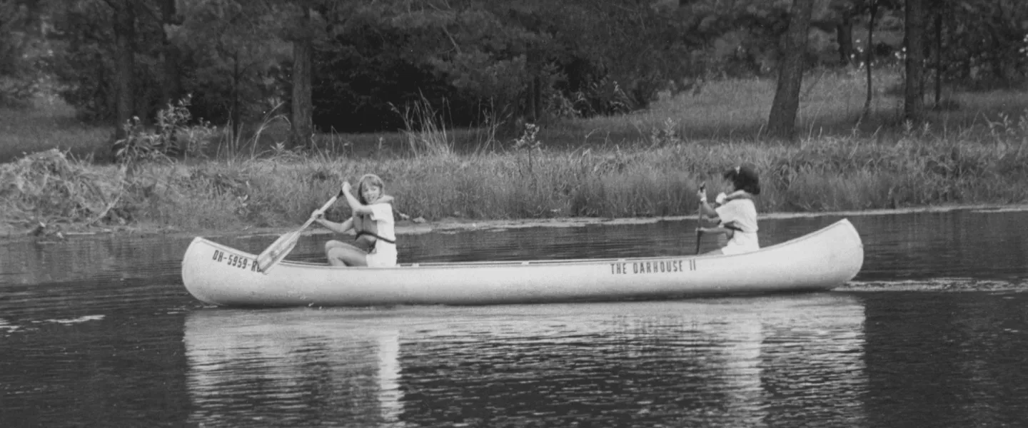 An old school photo of kids canoeing at camp