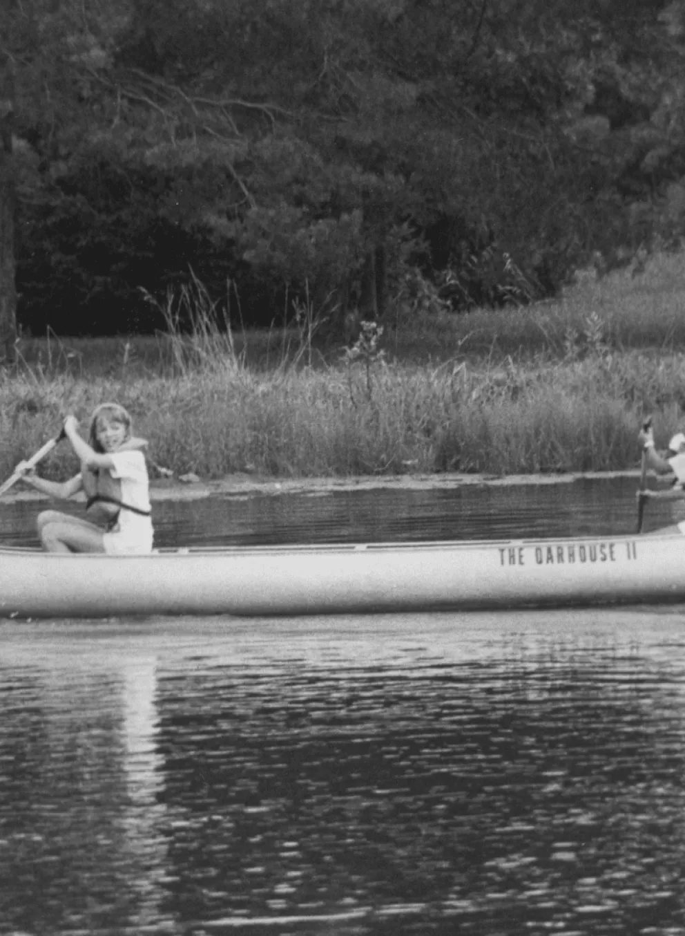 An old school photo of kids canoeing at camp