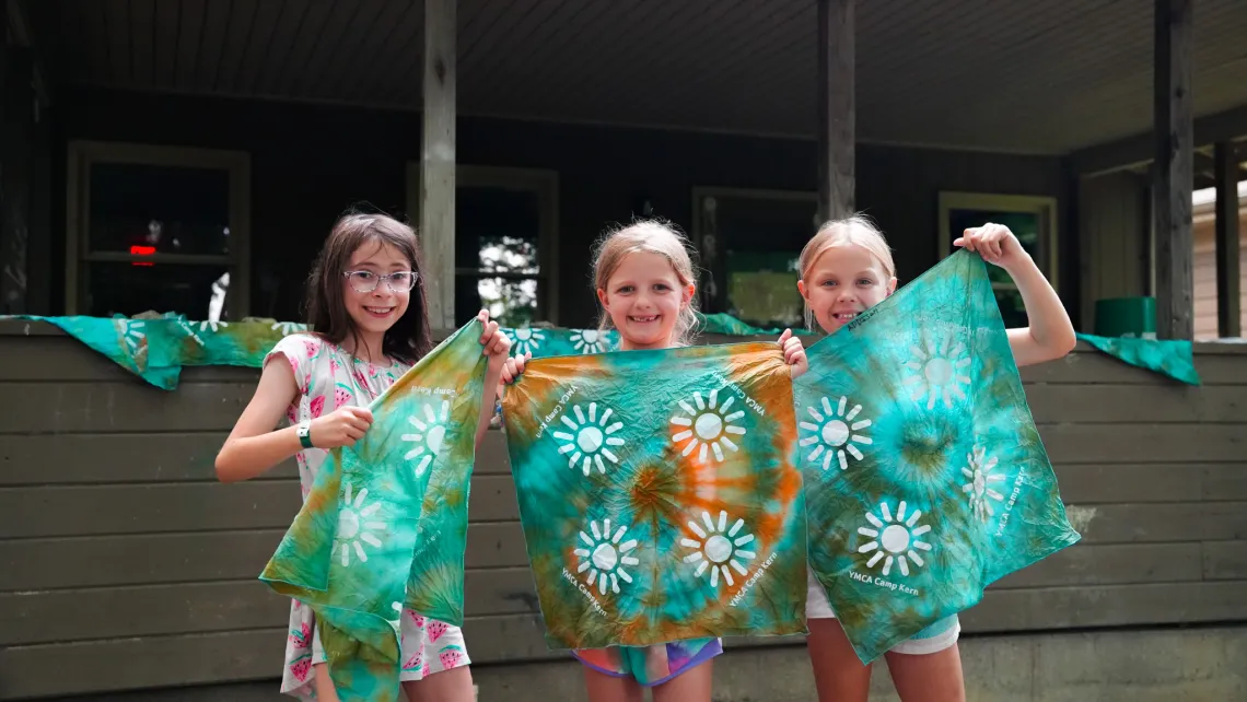 girls holding up art at camp
