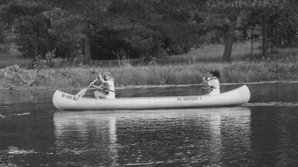 An old school photo of kids canoeing at camp